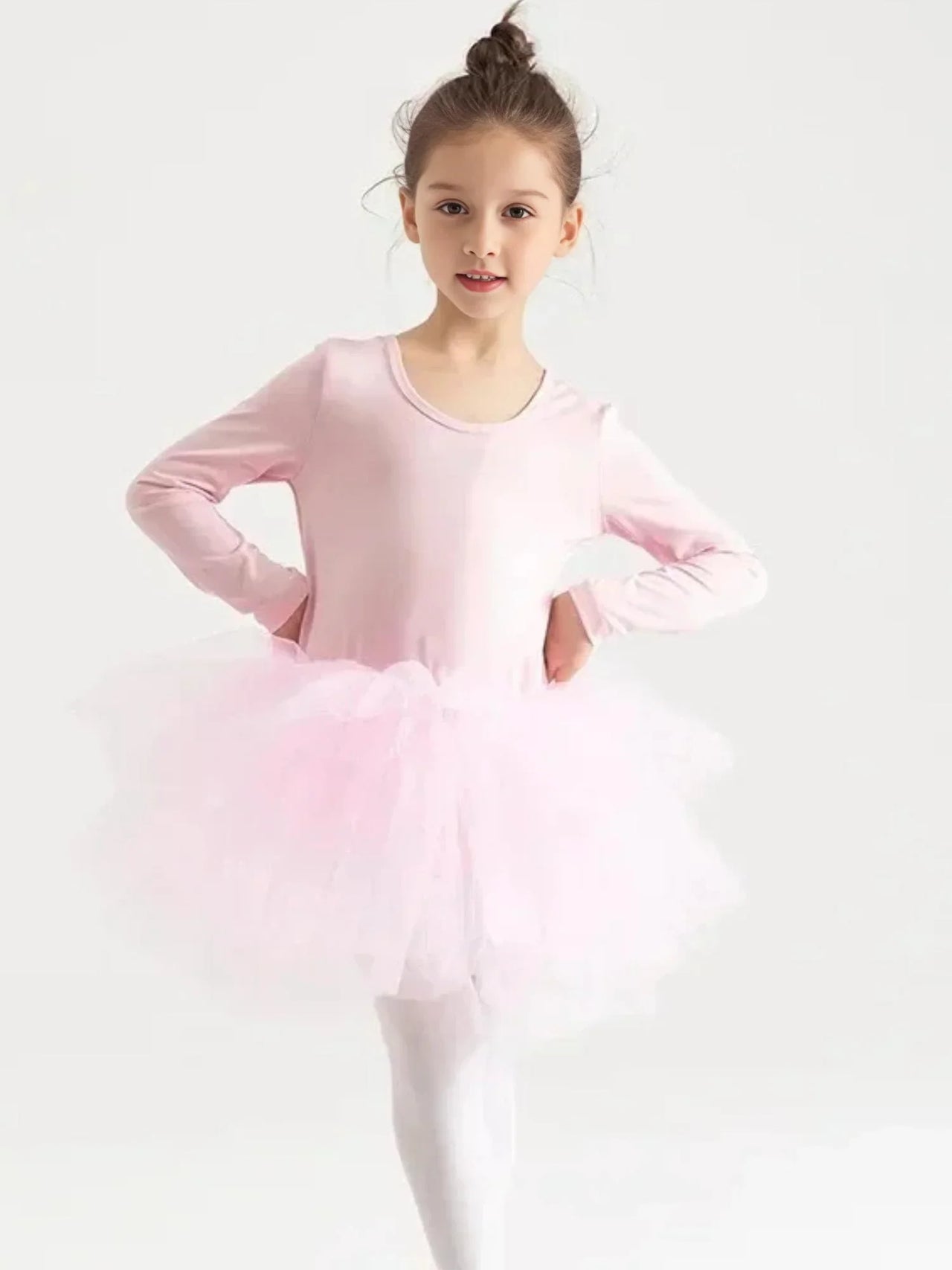 Young girl in a pink long sleeved ballet tutu dress on a white background