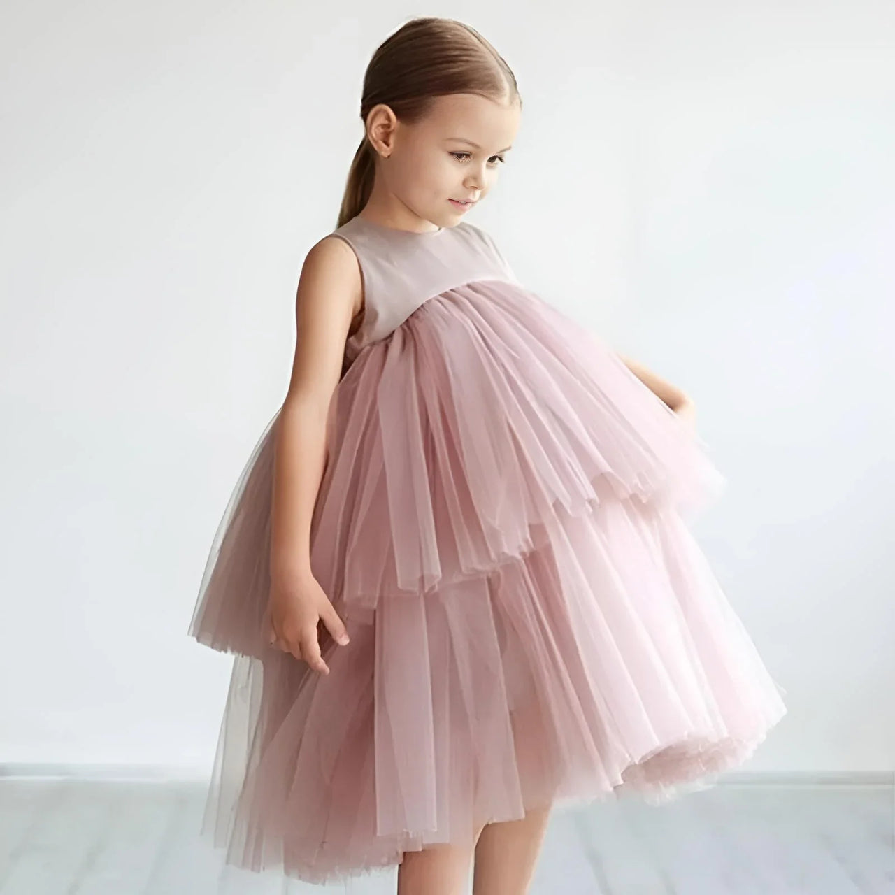 Young girl wearing a pink tulle dress against a white background