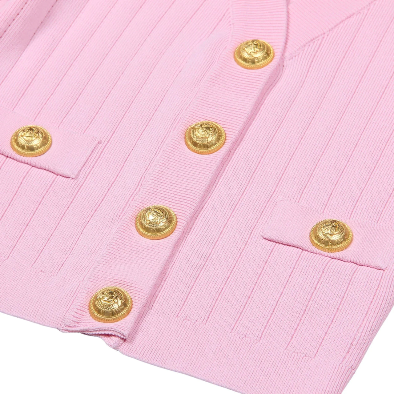 Close-up of a pink cardigan with a gold button on a white background