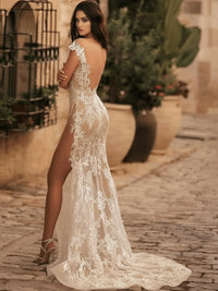 Thumbnail for Woman in a lace wedding dress standing on a cobblestone street with plants in the background
