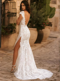Thumbnail for Woman wearing a white lace wedding dress with a high slit on a stone path.