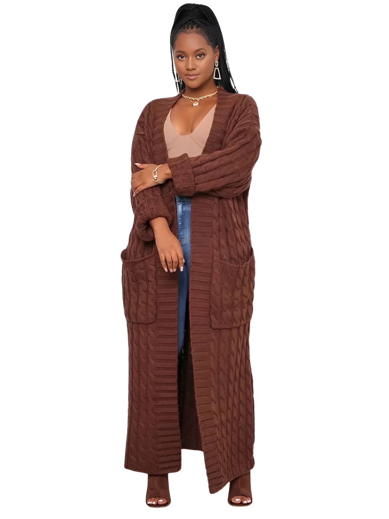 Woman wearing a long brown cardigan over a sheer top and blue jeans on a white background