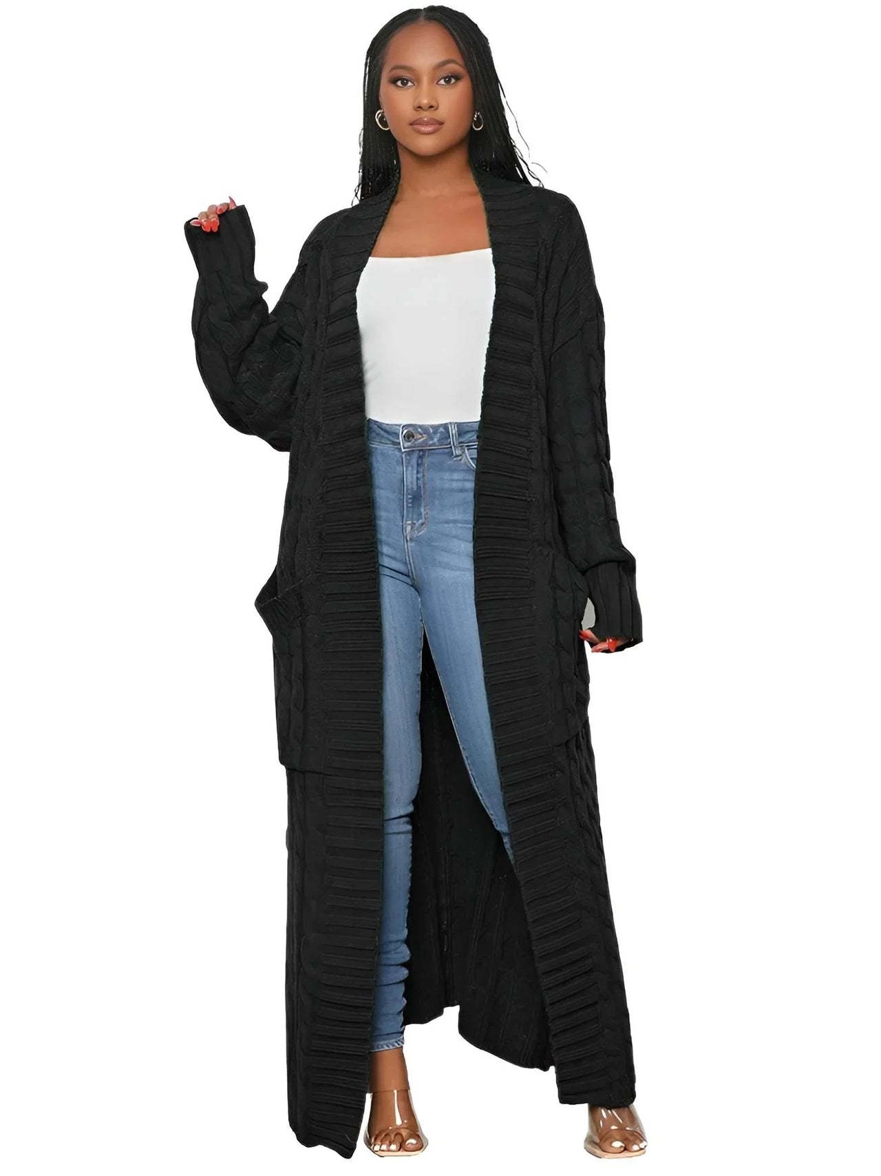 Woman wearing a long black cardigan over a white top and blue jeans on a white background