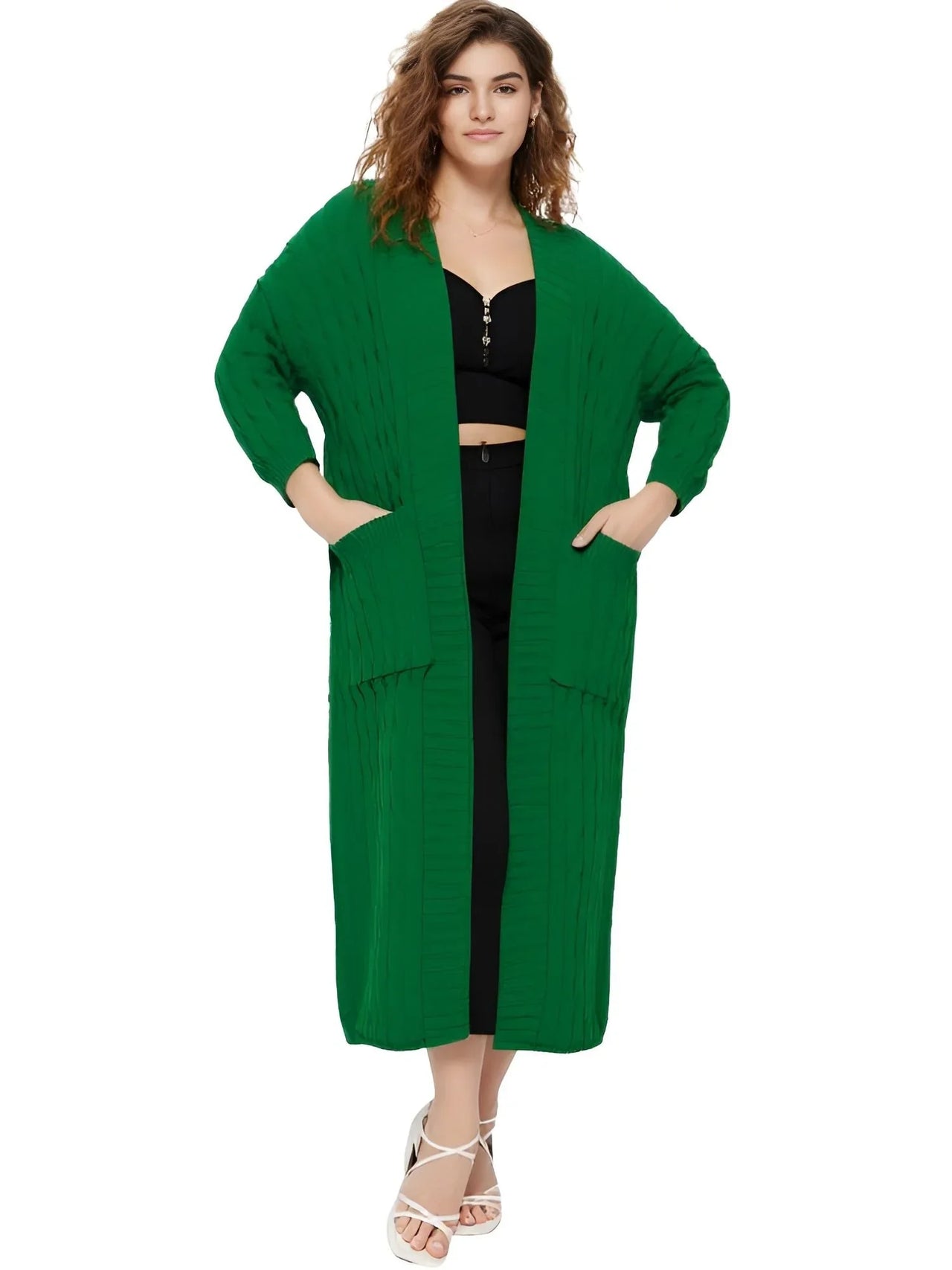 Woman wearing a long green cardigan over a black outfit on a white background