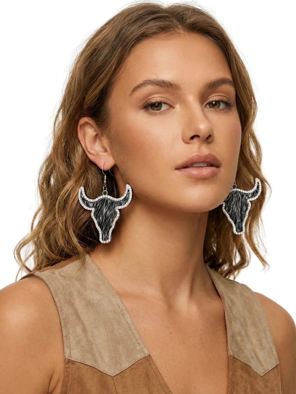 Woman wearing large earrings with bull head designs on a plain background