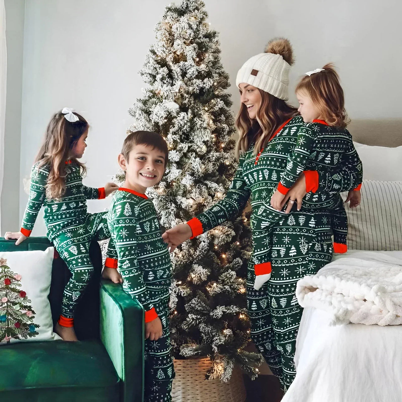 Family in matching green Christmas pajamas standing around a decorated Christmas tree.