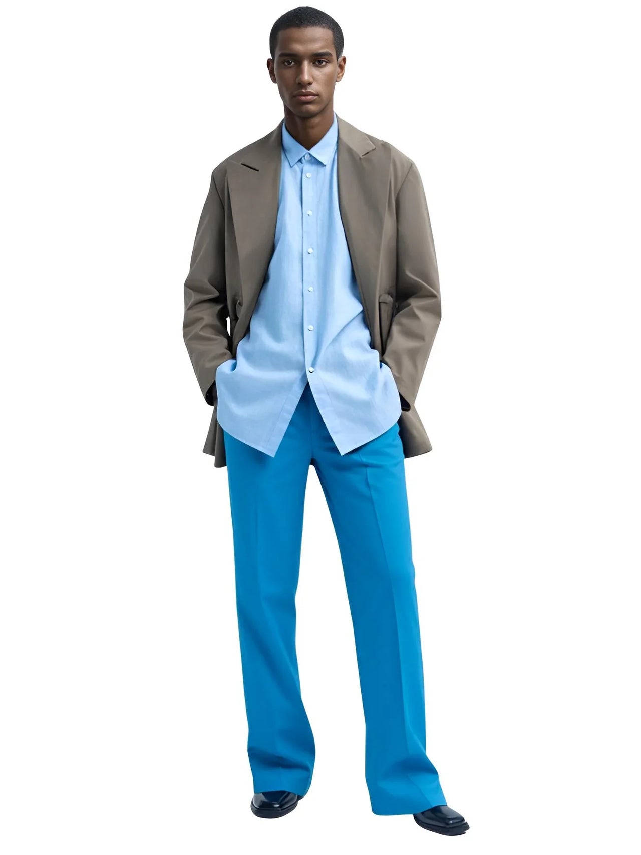 Man wearing a light blue shirt, blue pants, and a brown jacket on a white background