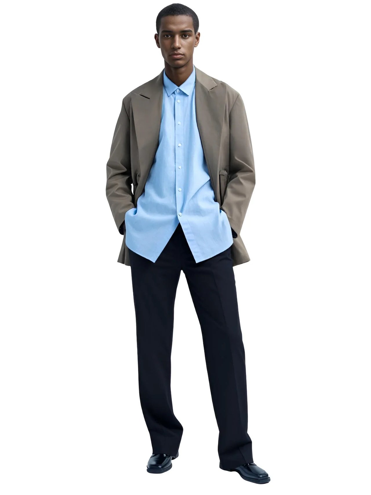 Man wearing a light brown blazer, light blue shirt, and black dress pants on a white background