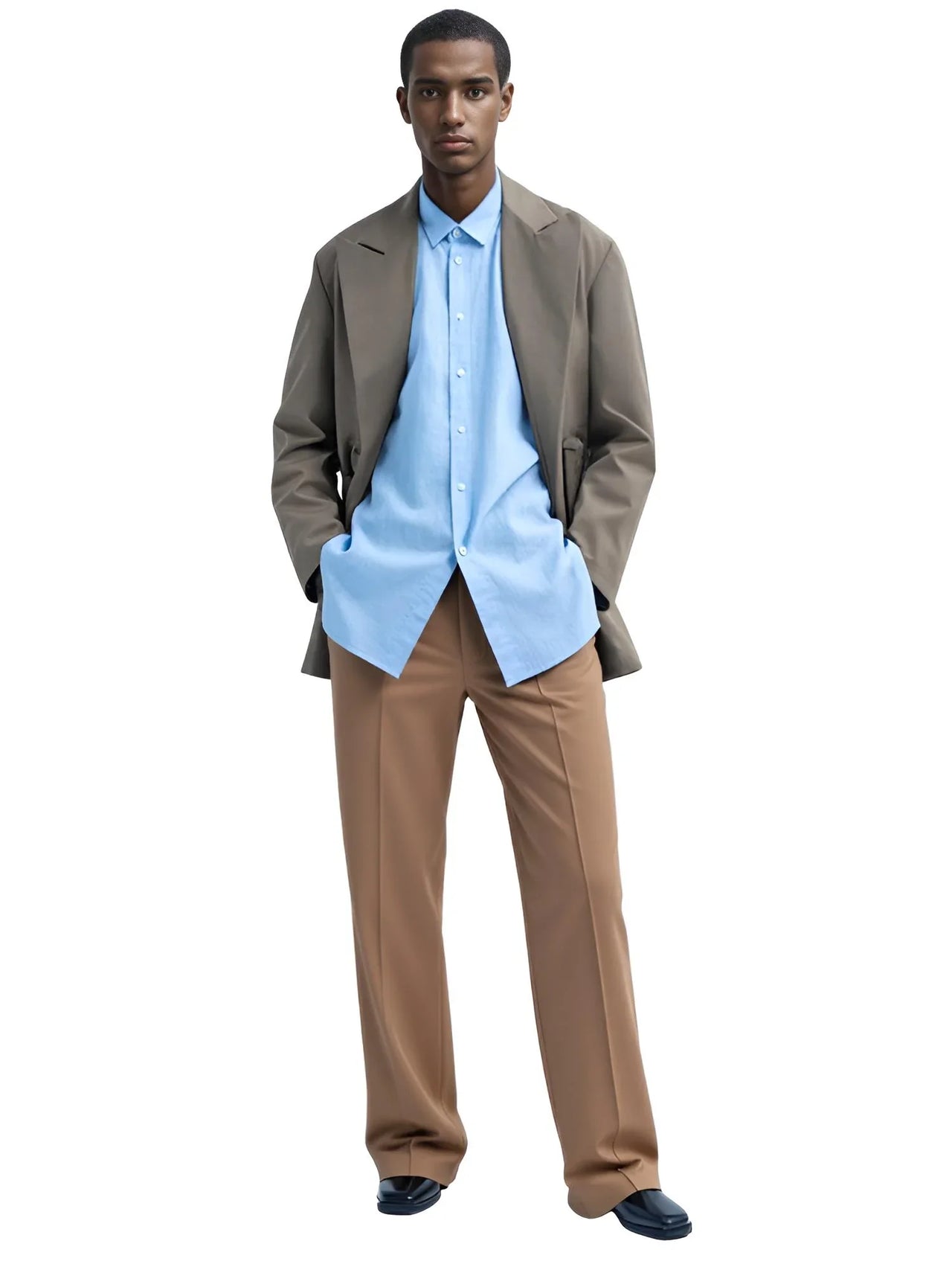 Man wearing a light blue shirt, brown jacket, and khaki pants on a white background