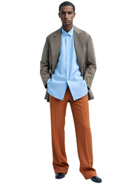Thumbnail for Man wearing a light blue shirt, brown jacket, and caramel pants on a white background