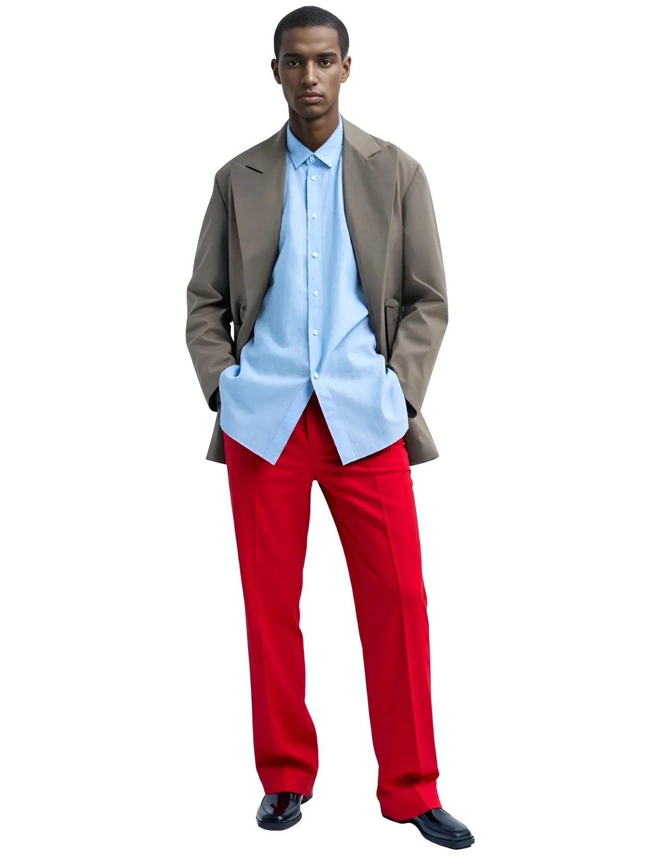 Man wearing a light blue shirt, red pants, and a brown jacket on a white background