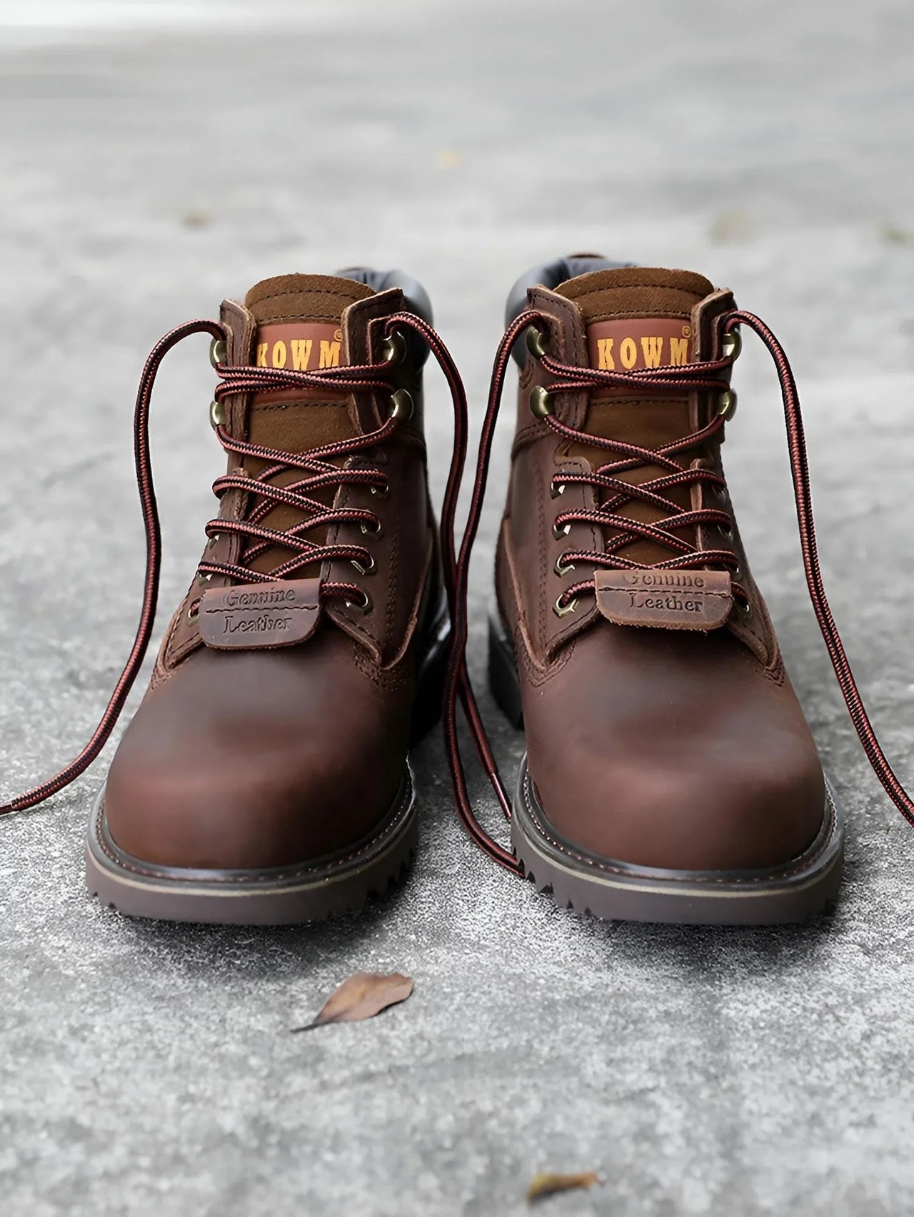 Pair of brown leather boots with laces on a gray surface