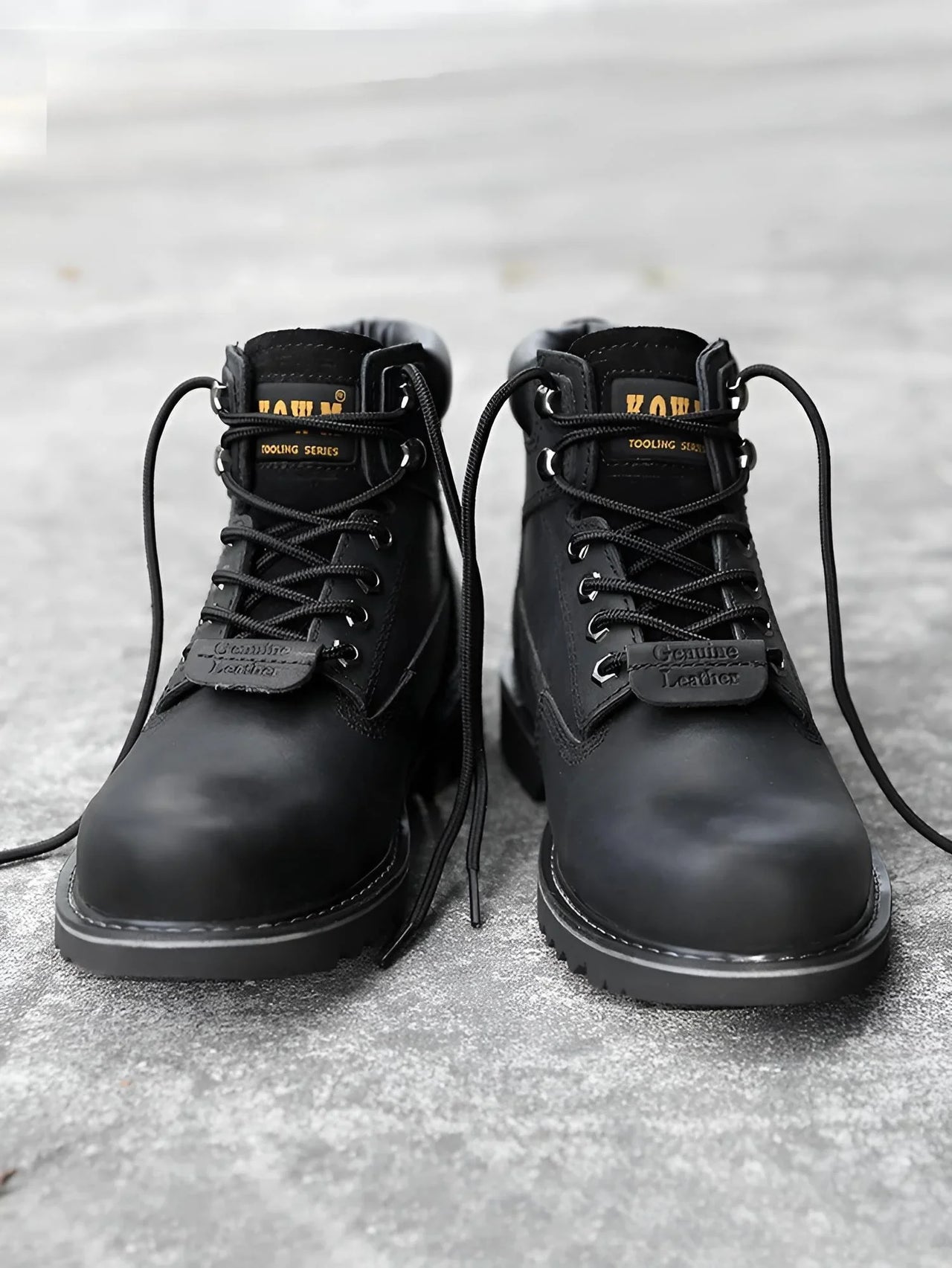 Pair of black leather boots with laces on a textured surface