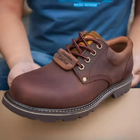 Thumbnail for Brown leather shoe with laces held by a person wearing blue pants.