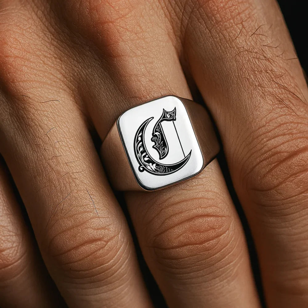 Silver ring with the initial 'c' on a hand