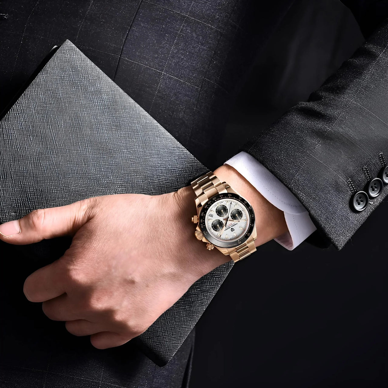 Person wearing a gold watch on a dark suit background