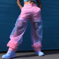 Thumbnail for Man wearing pink mesh pants and blue shoes against a blue wall.