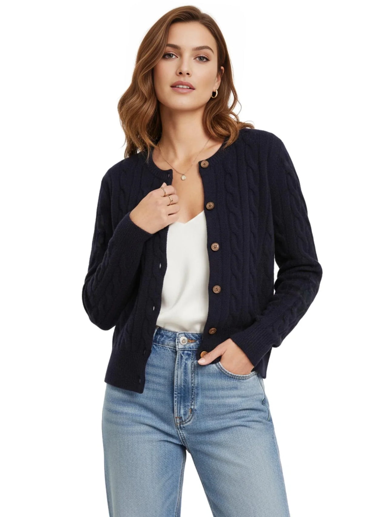 Woman wearing a navy cable knit cardigan over a white top and blue jeans on a white background