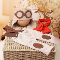 Thumbnail for Baby outfit with hat, bib, and booties on a woven basket with a blurred floral background