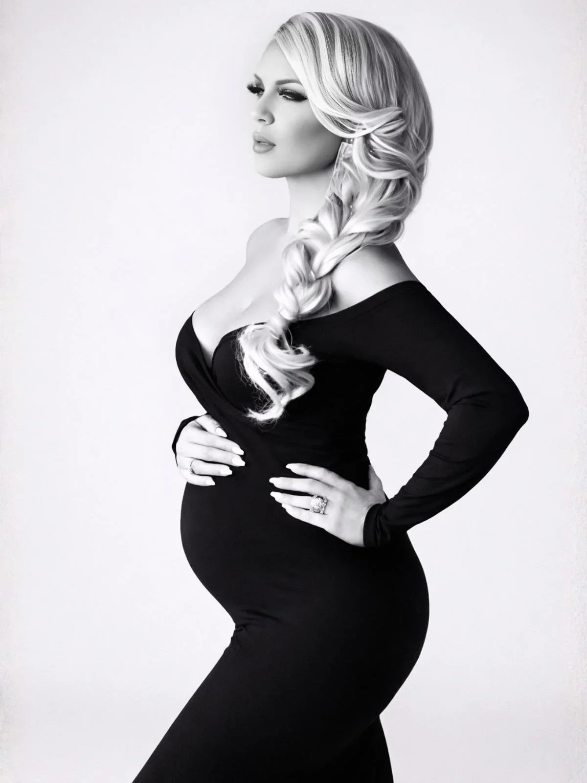 Woman in a black dress with styled hair against a white background