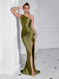 Thumbnail for Woman wearing an olive green one-shoulder draped maxi dress with a high slit in a white room.