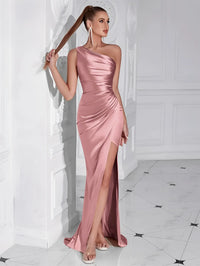 Thumbnail for Woman wearing a pink one-shoulder draped maxi dress with a high slit in a white room.
