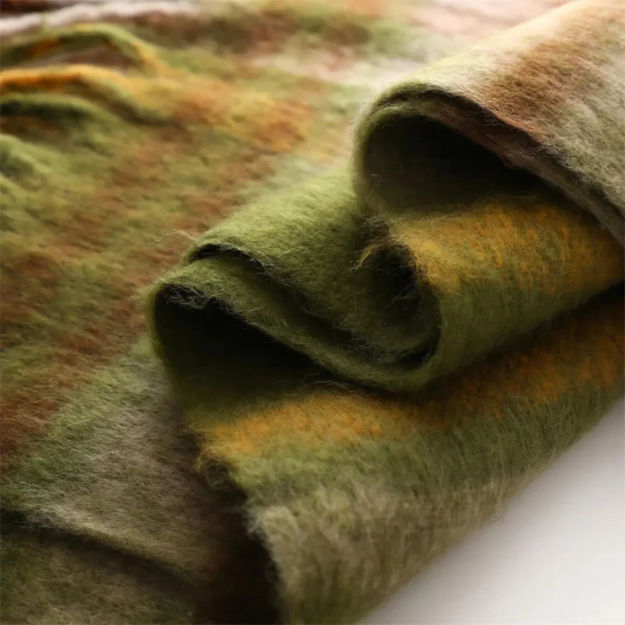 Close-up of a folded piece of green and brown scarf on a white surface