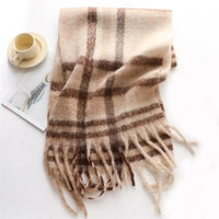 Thumbnail for Plaid scarf with fringes on a white surface with a cup and saucer.