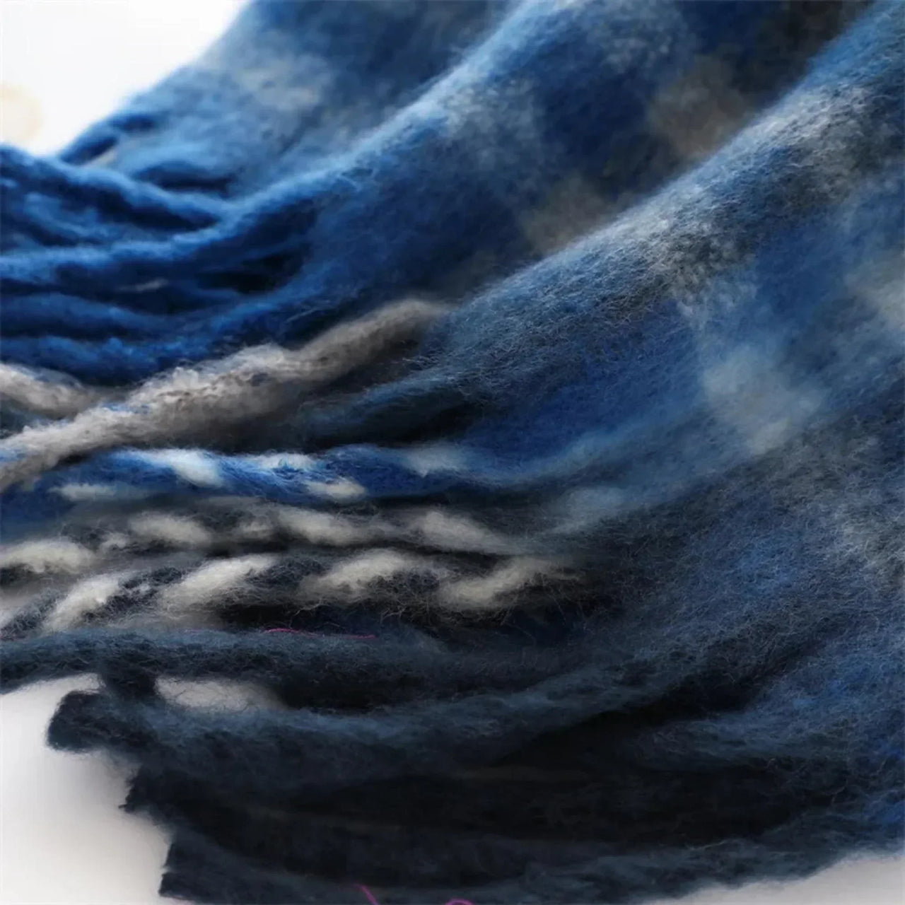 Close-up of a blue and gray plaid scarf with frayed edges.
