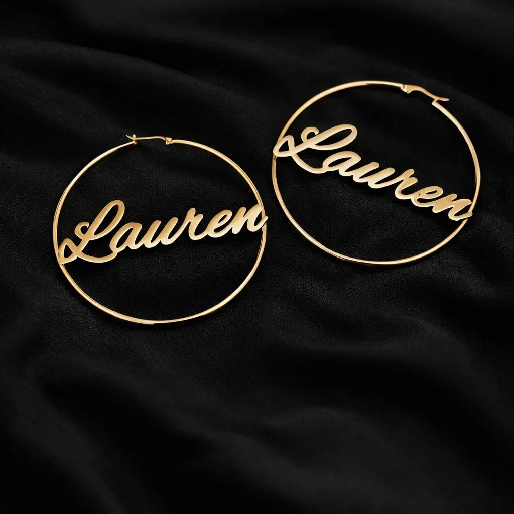 Gold hoop earrings with 'Lauren' engraving on a black fabric background