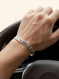 Thumbnail for Hand on car steering wheel wearing a silver bracelet with engraved design