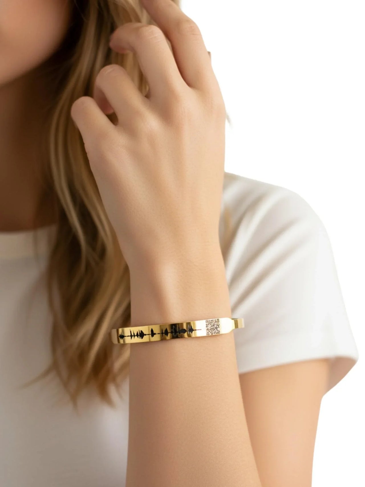 Gold voice bracelet with QR code on a person's wrist with a white background