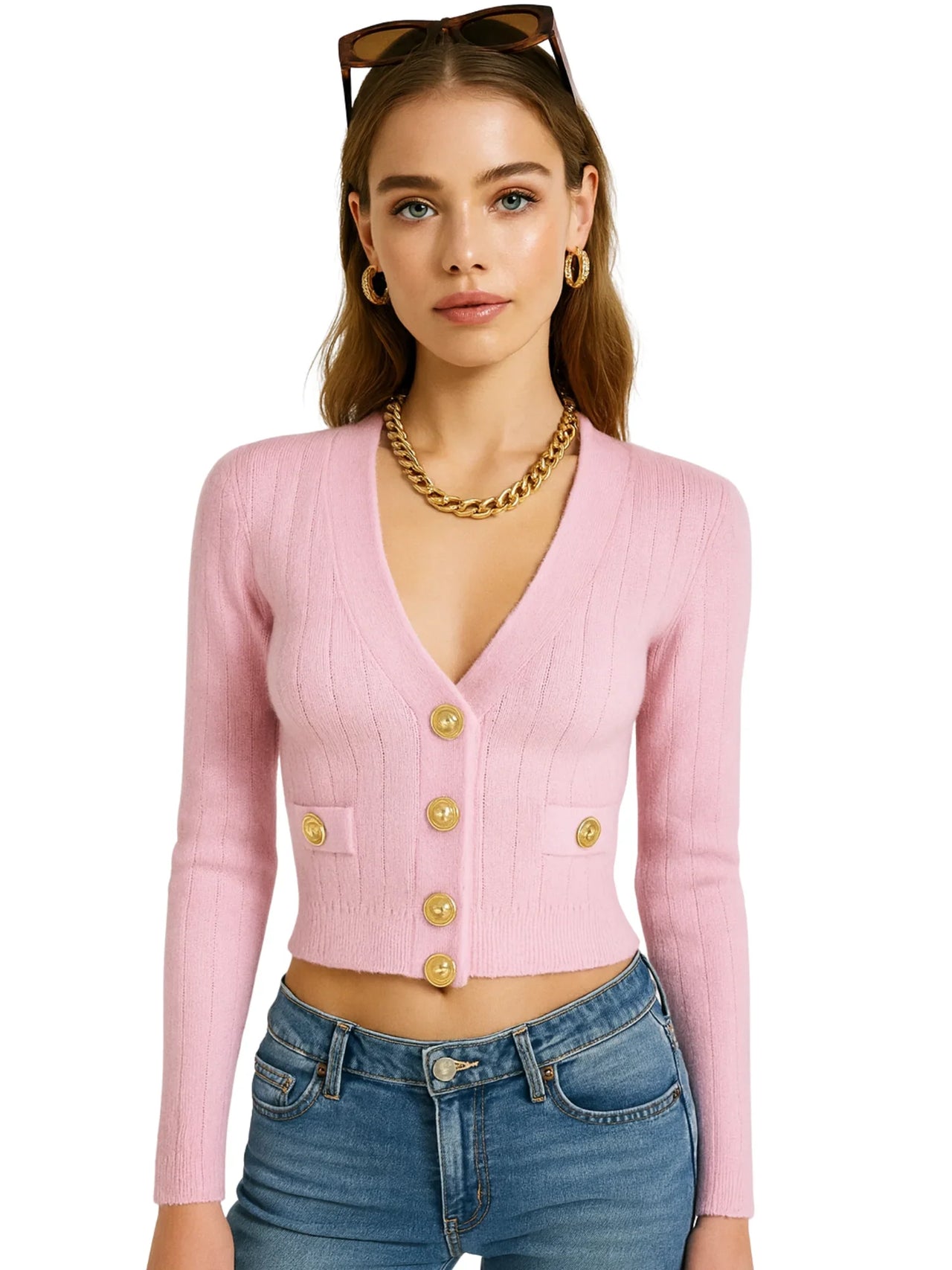 Woman wearing a pink cardigan with gold buttons and blue jeans on a white background