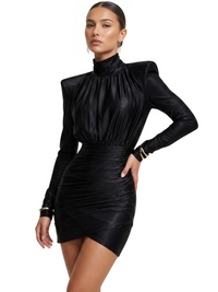 Thumbnail for Woman wearing a black long sleeved mini dress with high collar on a white background. 