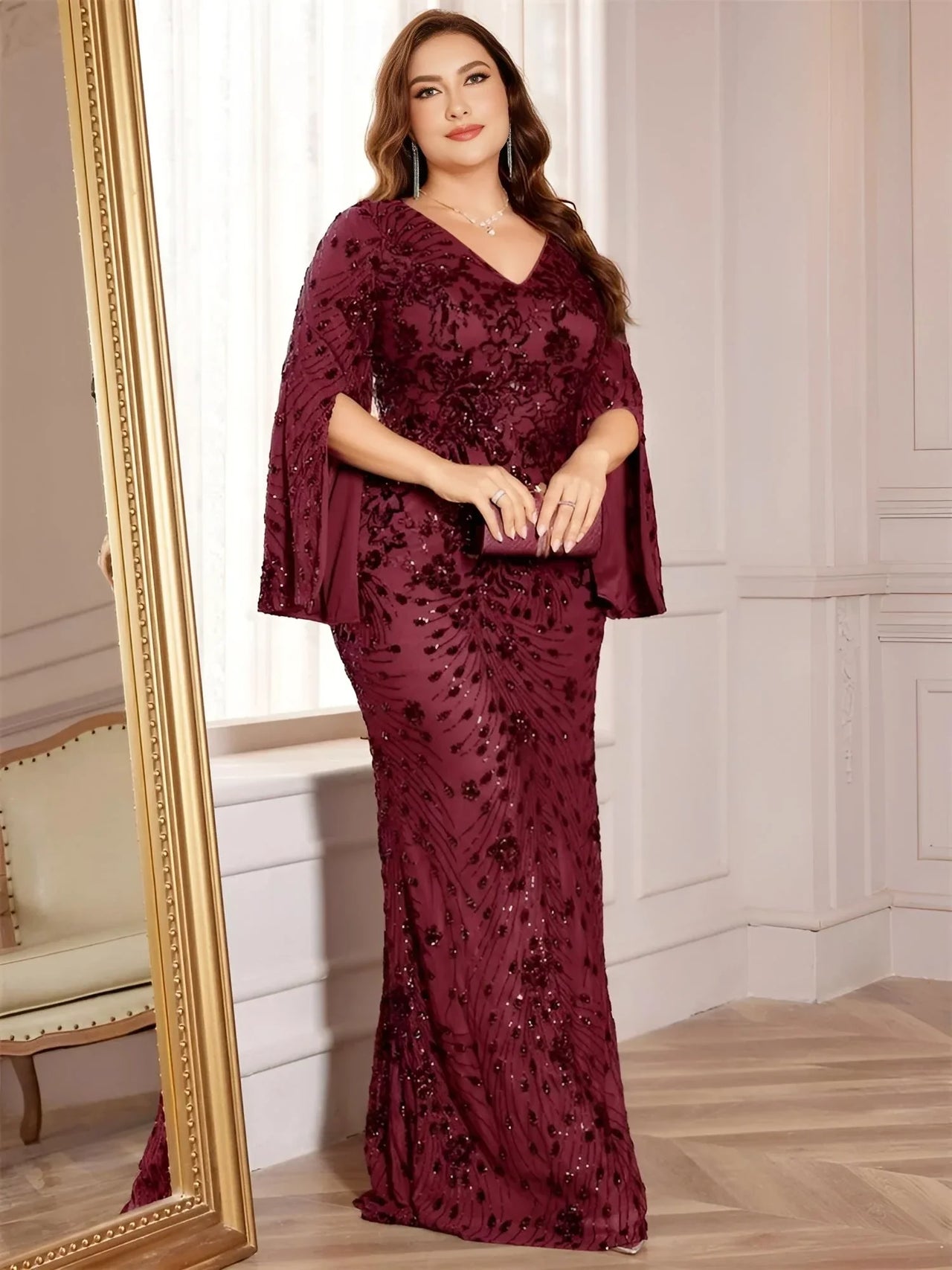 Woman in a burgundy evening gown standing in front of a mirror.
