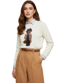 Thumbnail for Woman wearing a white pullover sweater with a teddy bear graphic, tan pants, and a brown belt on a white background