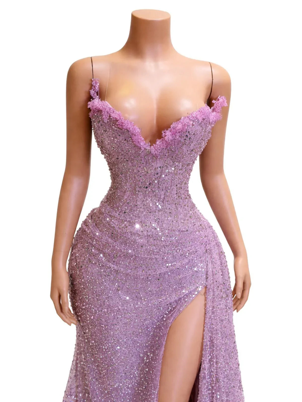 Woman wearing a strapless, purple sequin mermaid evening gown with a high slit on a white background