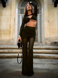 Thumbnail for Woman wearing a sheer 2 piece black pant set with a hollow out crop top on a white background