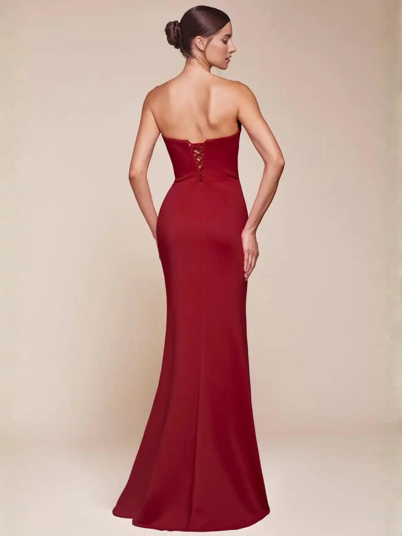 Woman wearing a strapless red evening gown on a beige background