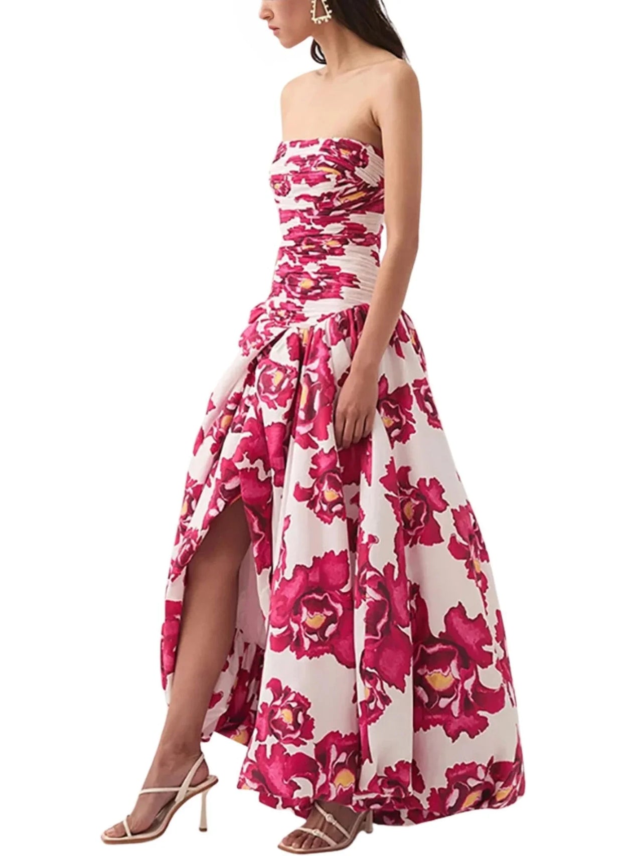 Woman wearing a red floral strapless long bubble dress with a high slit on a white background