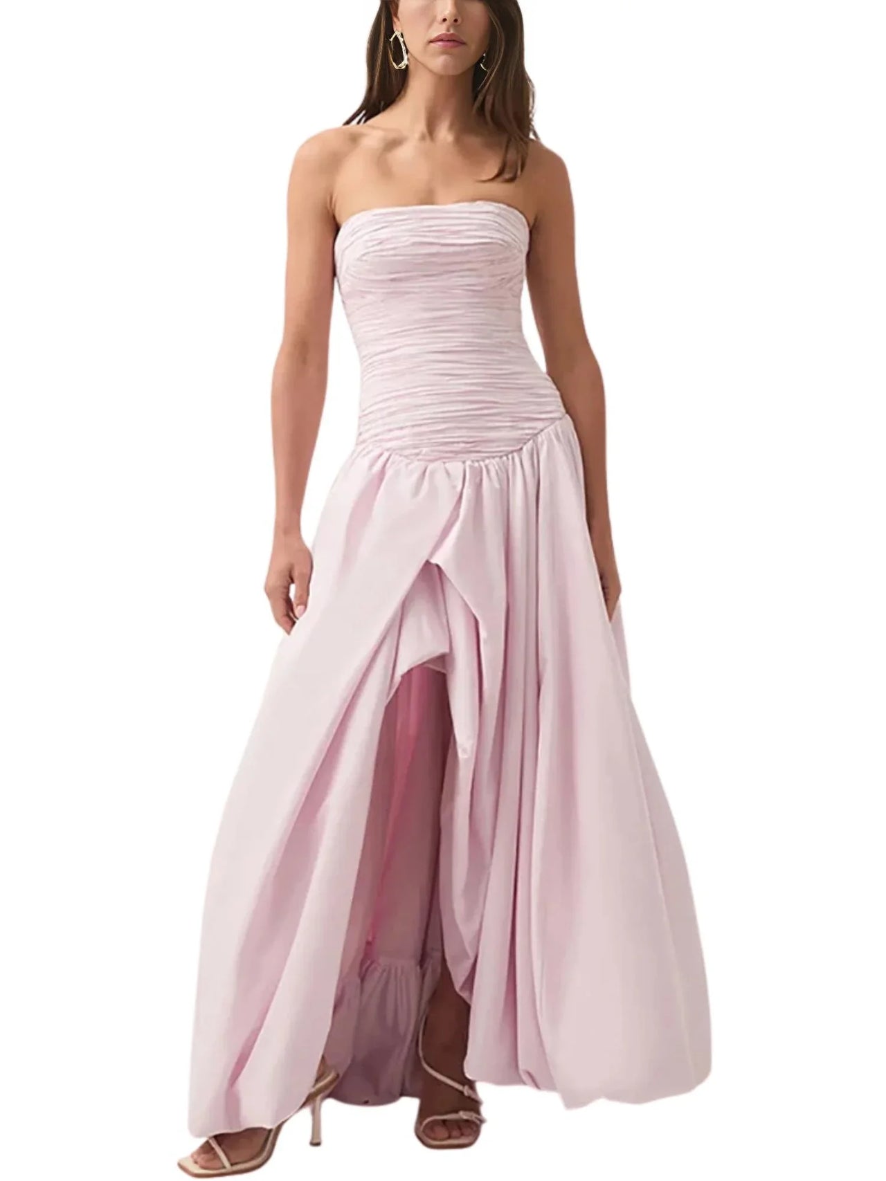 Woman wearing a pink floral strapless long bubble dress with a high slit on a white background 