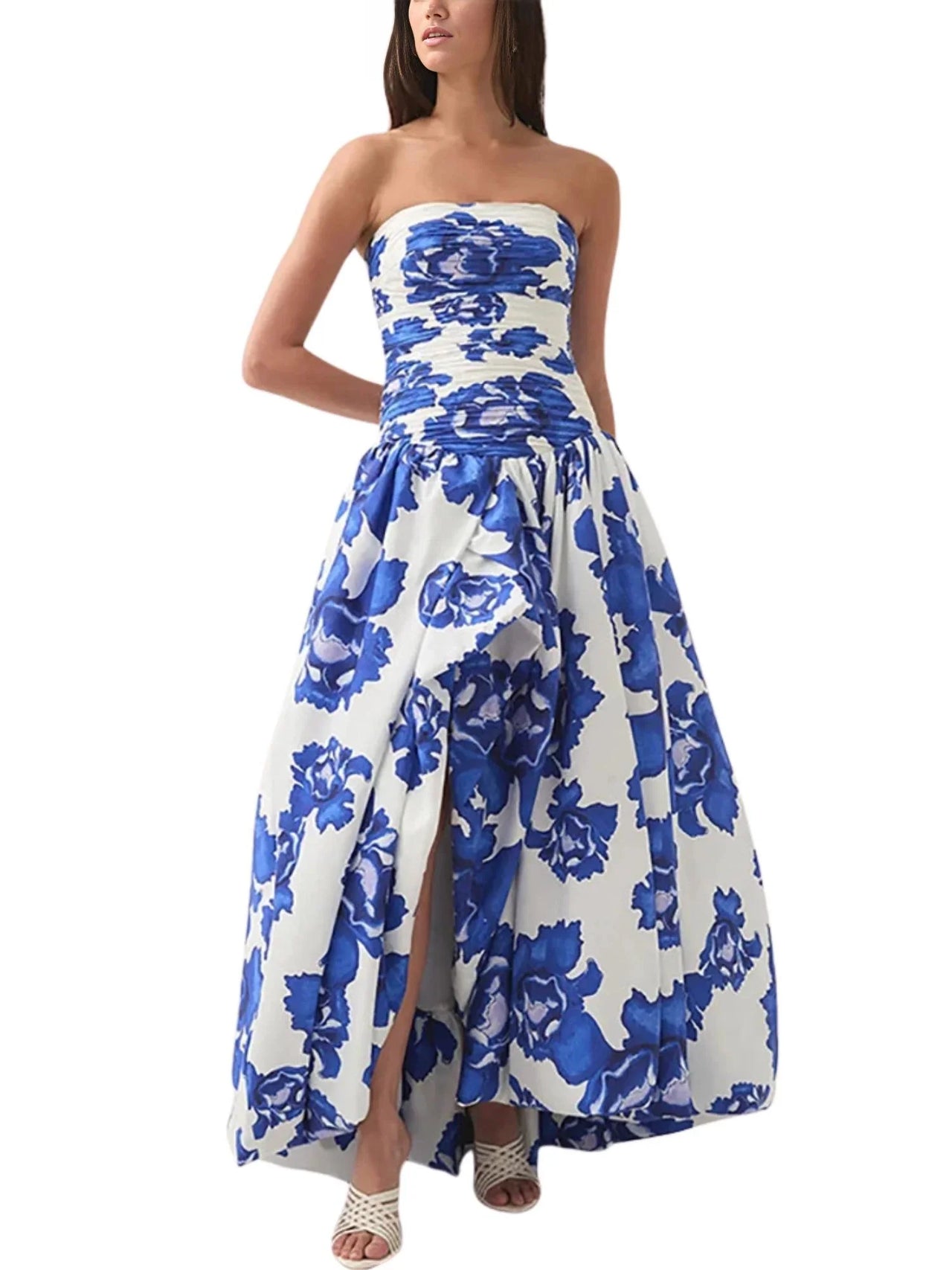 Woman wearing a blue floral strapless long bubble dress with a high slit on a white background
