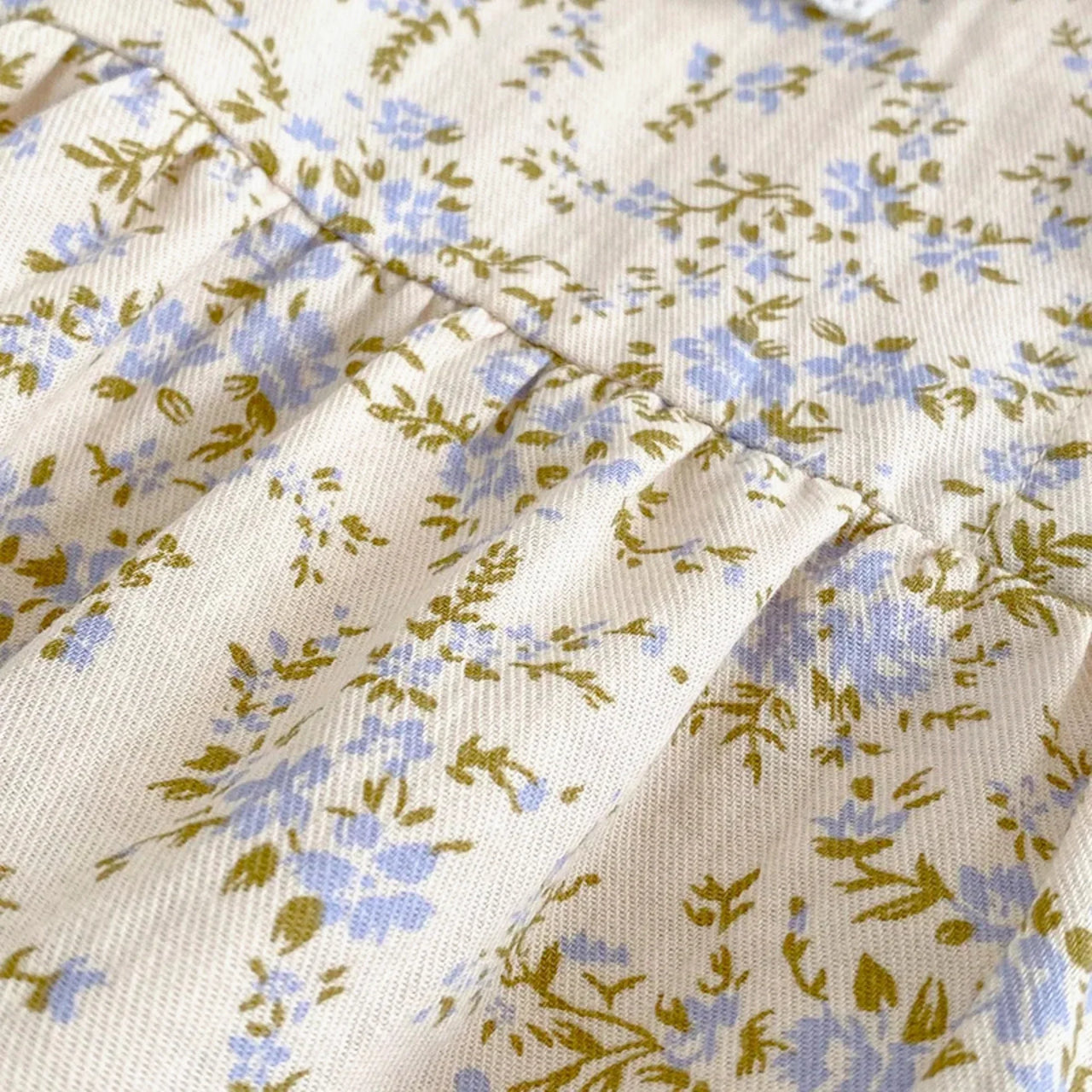 Close-up of floral fabric with blue and green flowers on a beige background