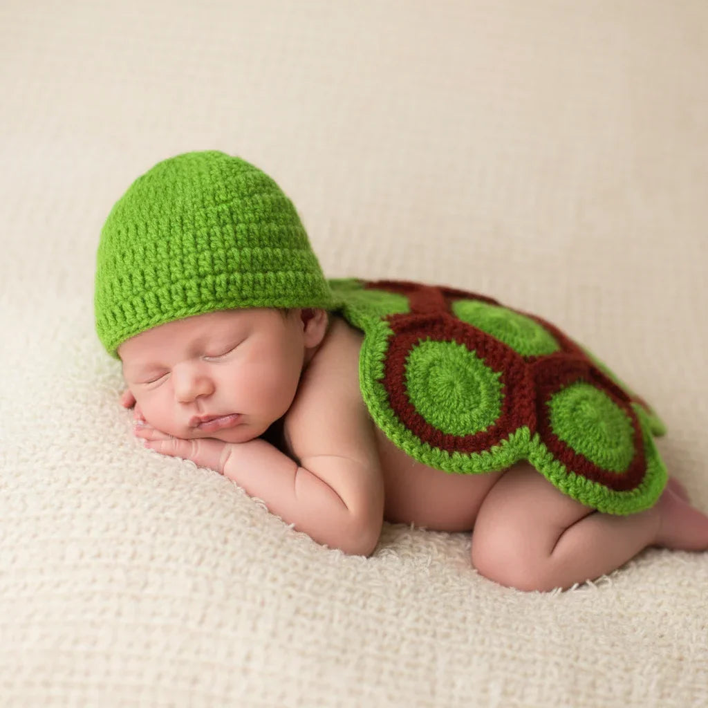 Newborn baby wearing a green crochet turtle costume on a beige blanket