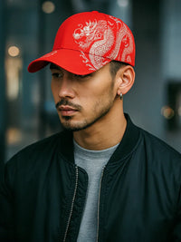 Thumbnail for Man wearing a red cap with a dragon design against a blurred background