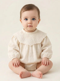 Thumbnail for Baby wearing a vintage cream- colored long sleeved romper on a beige background.