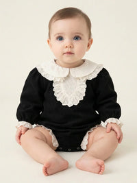 Thumbnail for Baby wearing a black romper with a white ruffled collar and cuffs on a plain background
