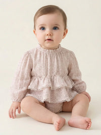Thumbnail for Baby wearing a pink romper with ruffled top and bloomers on a plain background