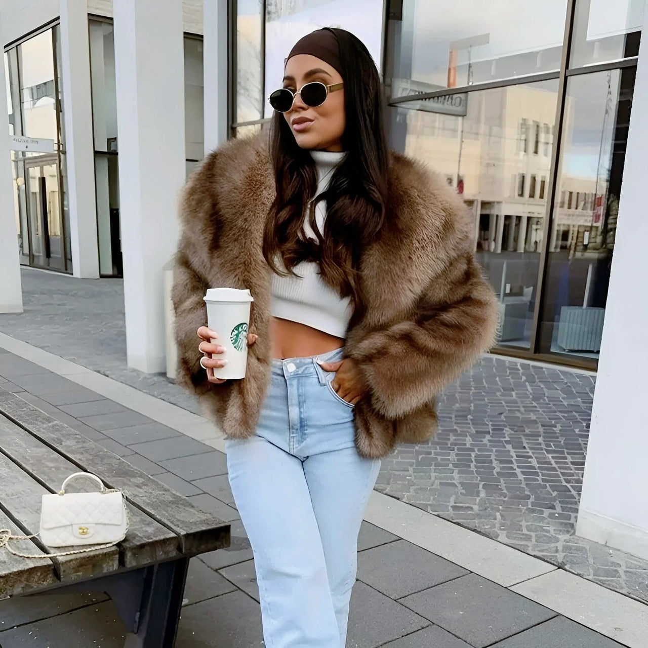 Woman in a brown faux fur coat holding a Starbucks cup outdoors