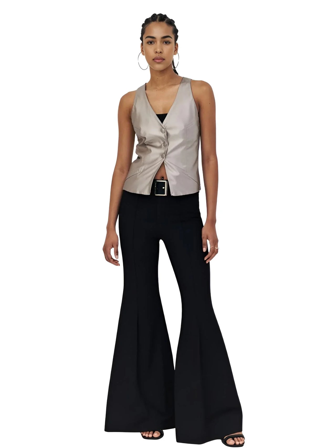 Woman wearing a metallic sleeveless top and black flared pants on a white background